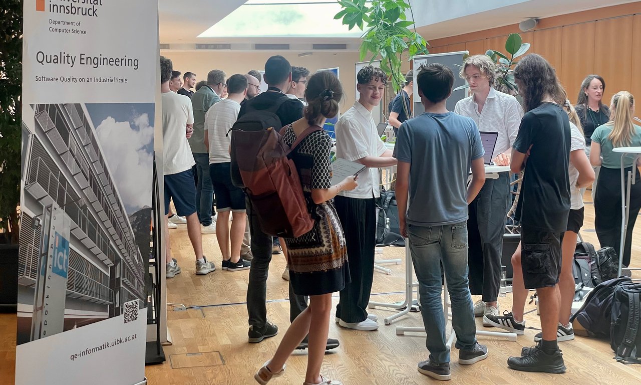 auf der rechten Seite, sieht man ein Roll Up und rechts Studierende, die gerade ihre Projekte präsentieren und zusammen sitzen.