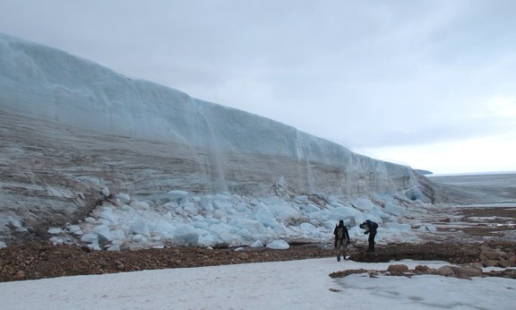 Zwei Personen stehen vor einem großen Eiscliff