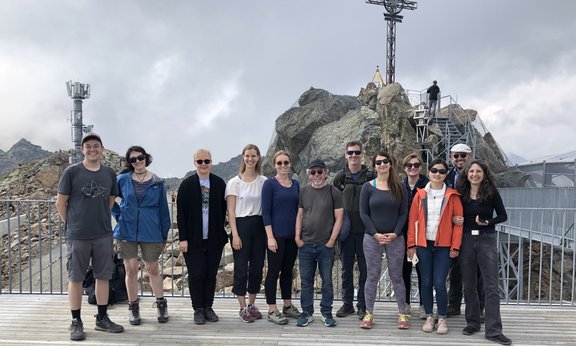 A group of people in front of the cross of the summit