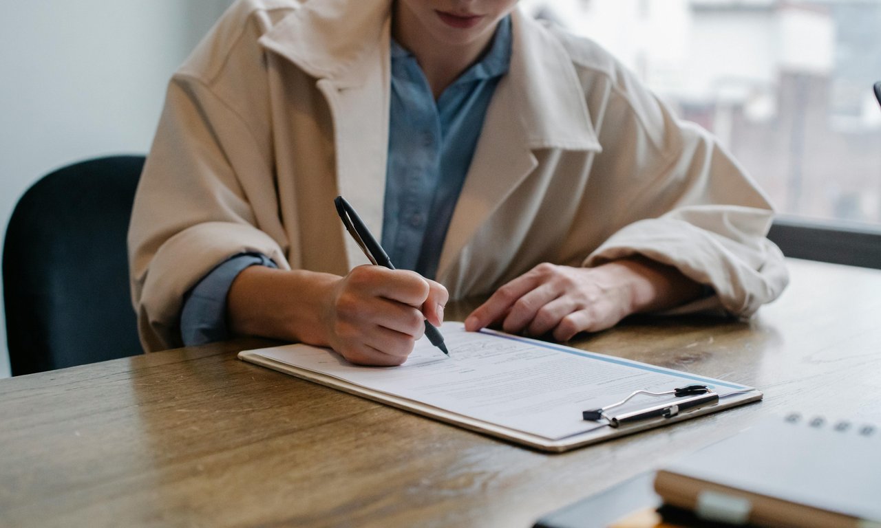 A woman sits at a table and fills out a questionnaire.