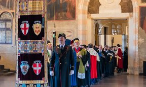 Festlich gekleidete Menschen tragen Wappen der Universität Padua