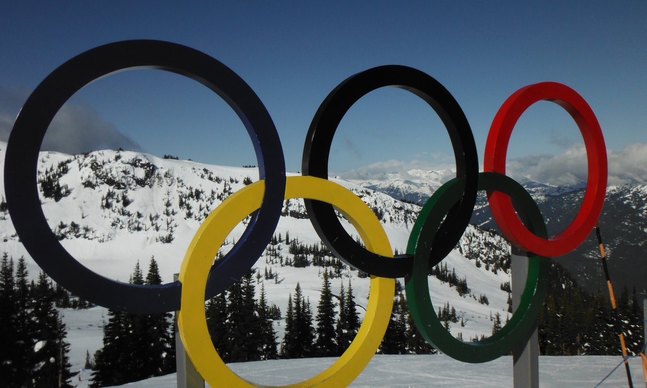Die olympischen Ringe vor einer winterlichen Landschaft.
