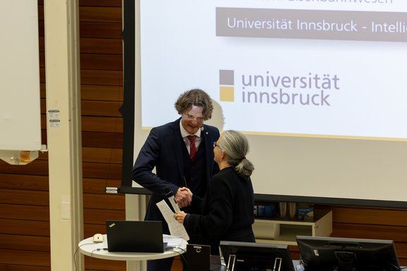 Wissenschaftlerin begrüßt Wissenschaftler mit Handschlag