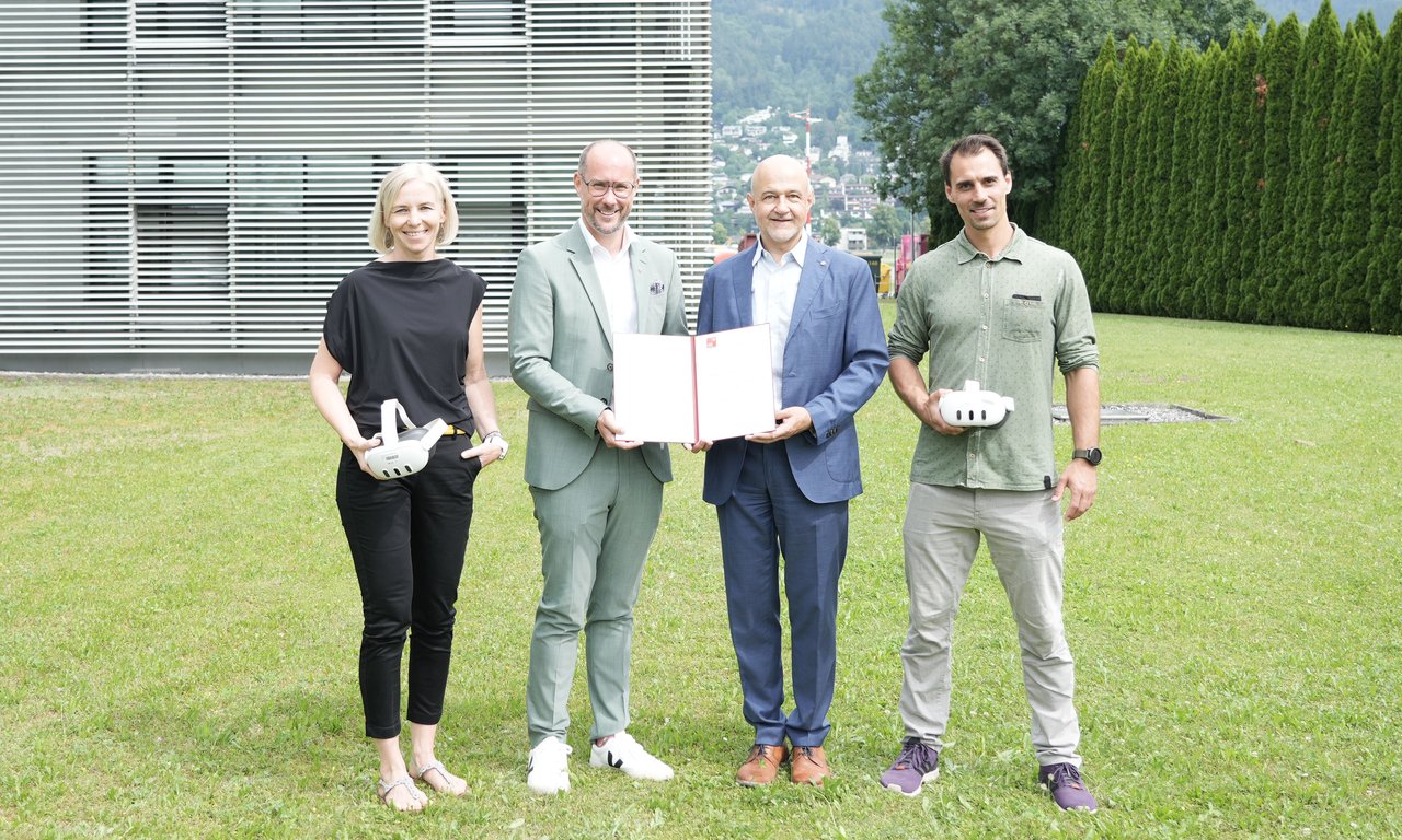 Vier Personen stehen auf einer Wiese und blicken zur Kamera
