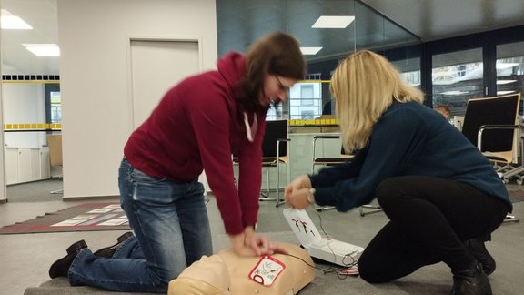 Eine Person übt Herzdruckmassage, eine andere bedient den Defibrillator