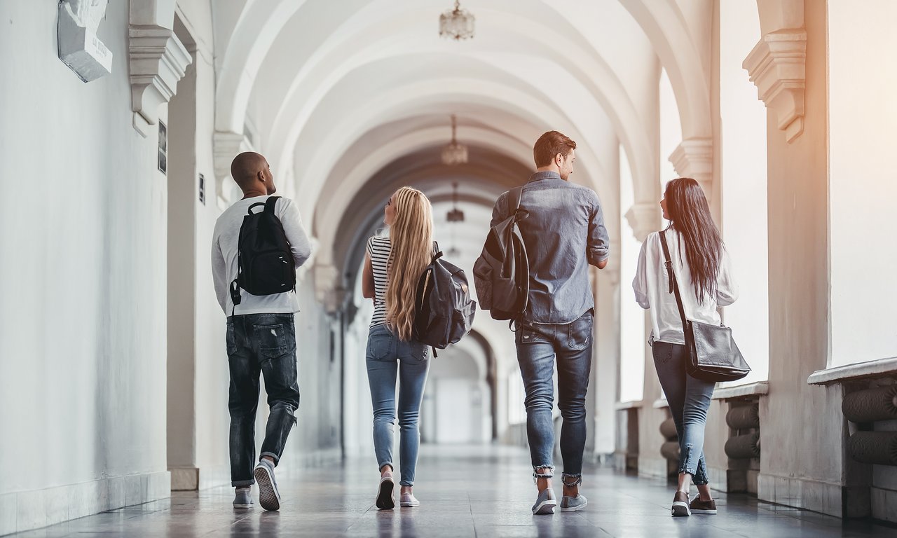 Das Bild zeigt vier Studierende in einem Gang.