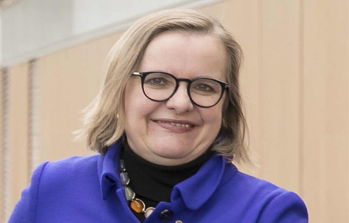Porträtfoto von Ulrike Tanzer in einem lila Kostüm und mit Brille