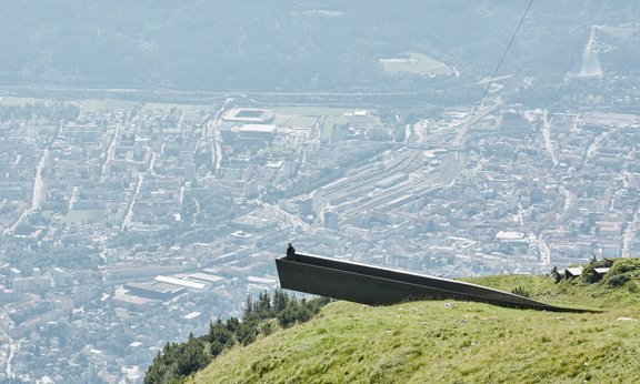 View of Innsbruck from the top of a nearby mountain. More mountains in the background.