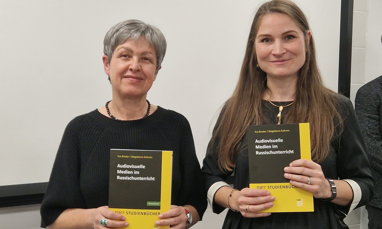 Zwei Frauen halten ein Buch in den Händen