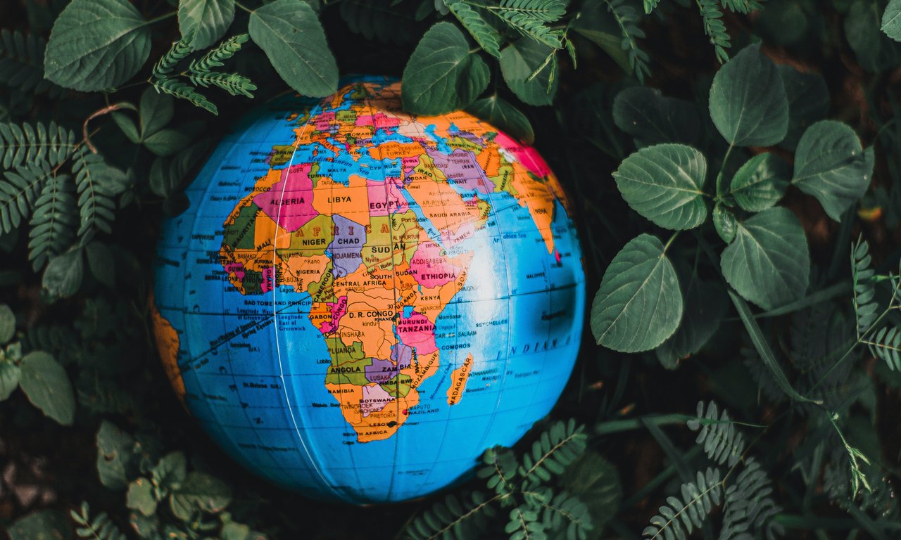 Ein Globus mit Afrika auf der sichtbaren Seite liegt in Blätter eingebettet auf dem Boden.
