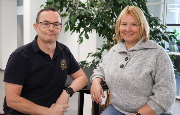 Markus Ammann und Katarzyna Ammann-Kapa sitzen vor einem grünen Baum