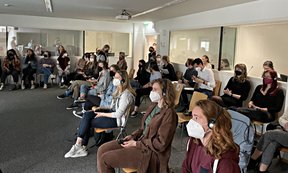 Studierende mit Maske in einem Seminarraum mit Übersetzungskabinen