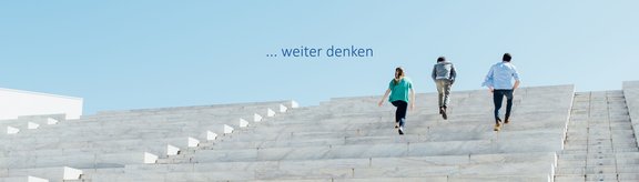 Zu sehen sind drei junge Erwachsene auf einer Stiege, darüber der Claim "... weiter denken".