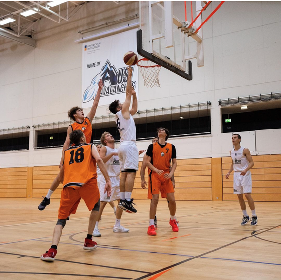 Basketballspiel in einer Halle; Szene zeigt einen Spieler beim Korbwurf