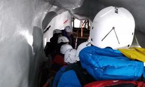 Personen mit Helmen in einer Eishöhle.