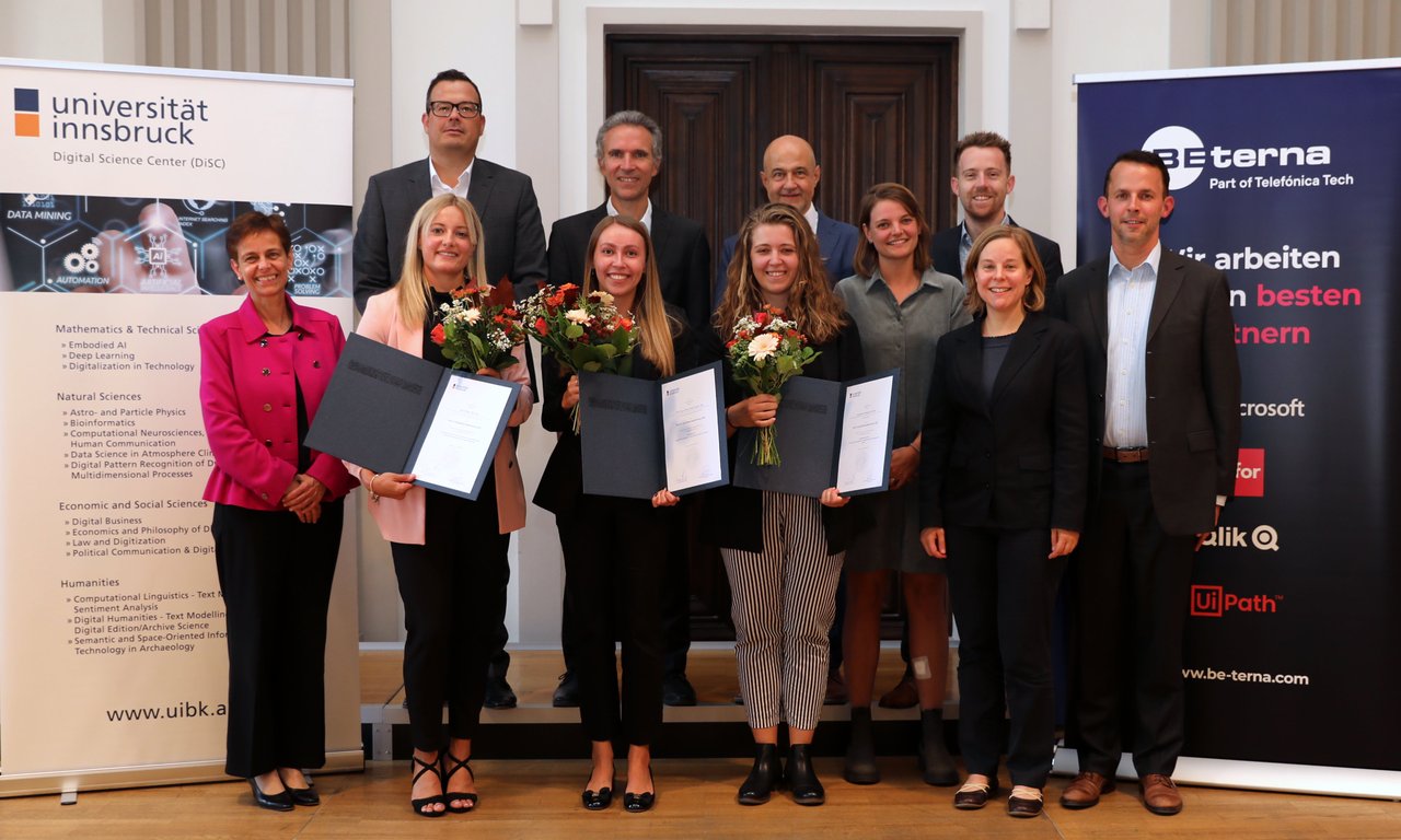Elf Personen stehen für ein Gruppenfoto auf der Bühne der Aula im Hauptgebäude.