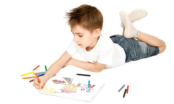 Kleiner Junge, der am Boden liegt und ein Bild malt.