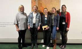 Zu sehen sind fünf Mitglieder der Theologischen Fakultät Innsbruck bei der Pastoraltagung. Sie stehen vor einer Wand mit einem großen Bild.