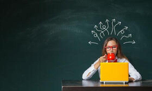 Frau mit Kaffee und Laptop, hinter ihr einen Tafel mit Gedankenlinien