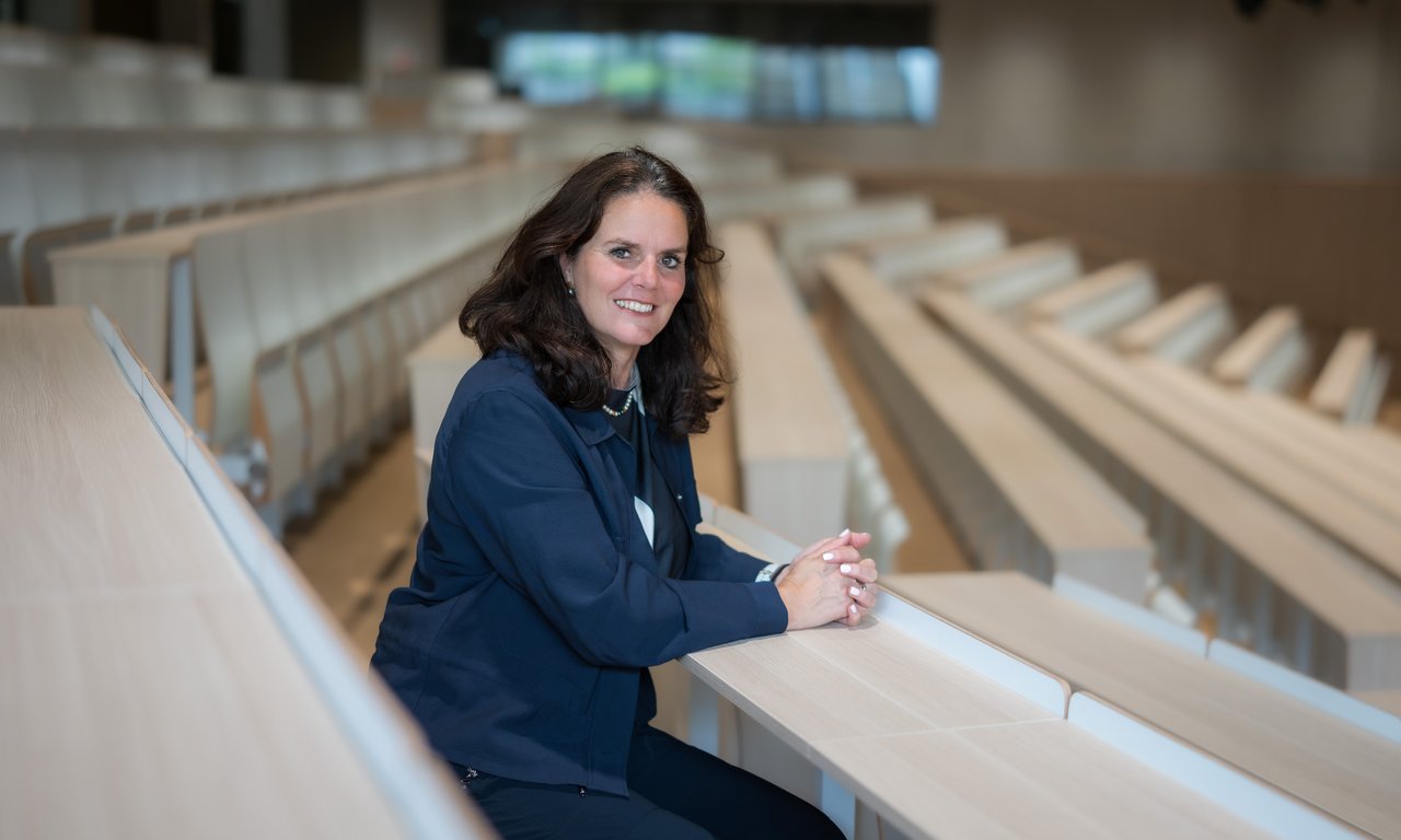 Gabriele Schauer sitzt in einem Hörsaal und schaut in die Kamera