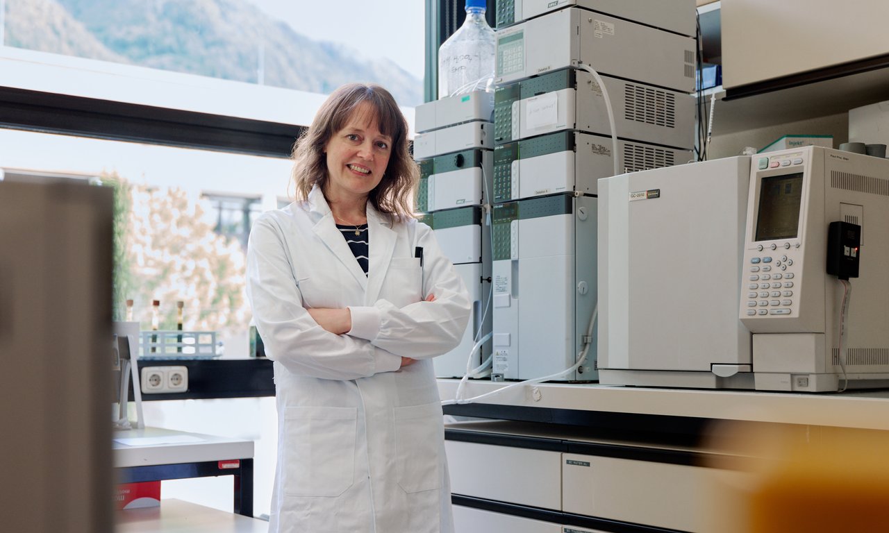 Eva Maria Prem steht in die Kamera blickend in weißem Laborgewand in ihrem Labor.