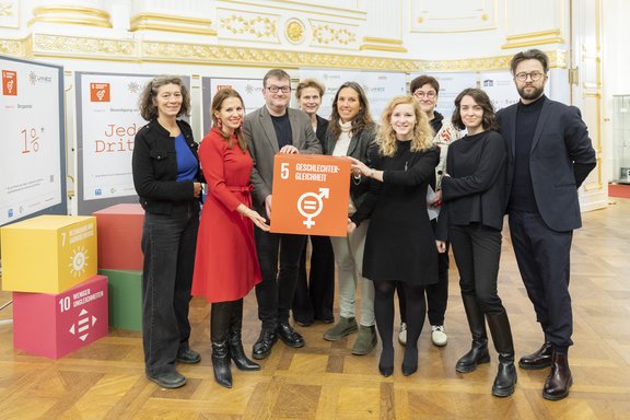 Gruppenfoto SDG 5-Infotag im österreichischen Parlament mit einem orangenen SDG 5 Würfel in der Mitte