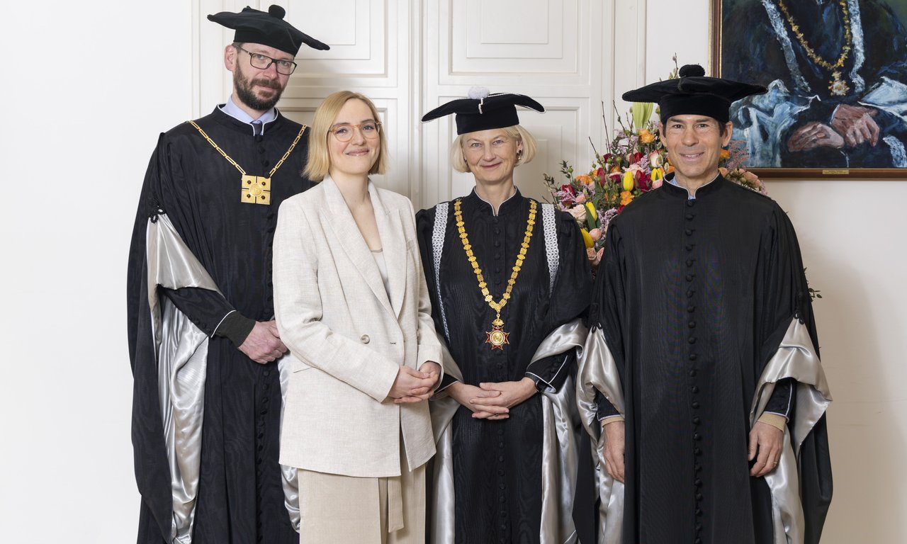 Gruppenfoto mit vier Personen, drei davon in Talaren.