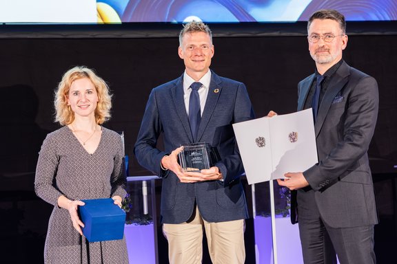 Drei Personen mit Urkunden in der Hand