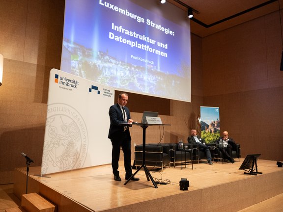 Foto von Paul Konsbruck auf der Bühne und Publikum