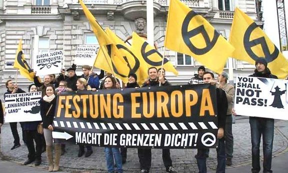 Foto einer Demonstration; Die Identitäre Bewegung hat den griech. Buchstaben Lambda – Symbol für "Lakedaimon", alter Name für Sparta – als ihr Symbol gewählt, in der Überzeugung, dass spartanische Soldaten dieses Symbol auf ihren Schilden trugen.