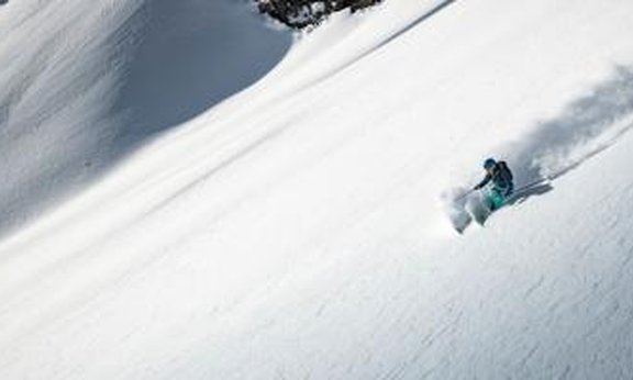 Person fährt mit Ski einen schneebedeckten Hang hinunter