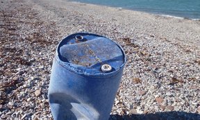 Ein zerbeulte, blaue Plastiktonne an einem verlassen Strand in der Arktis