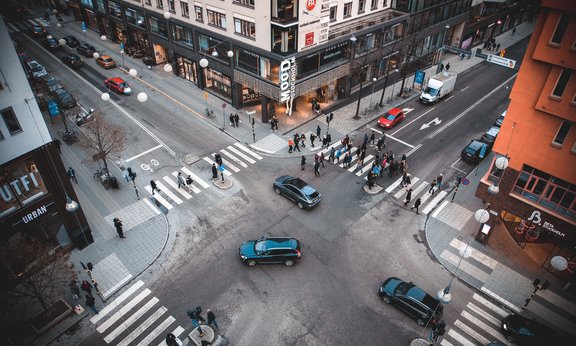 Kreuzung mit Autos und Personen auf Zebrastreifen
