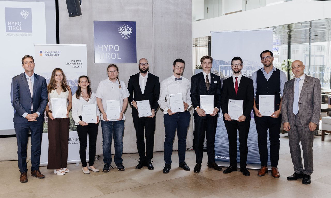 Daniel Senn (Hypo Tirol) und VR Gregor Weihs mit den acht der zehn ausgezeichneten Dissertand:innen.