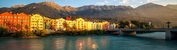 River "Inn" with old colourfull buildings and mountains in the background