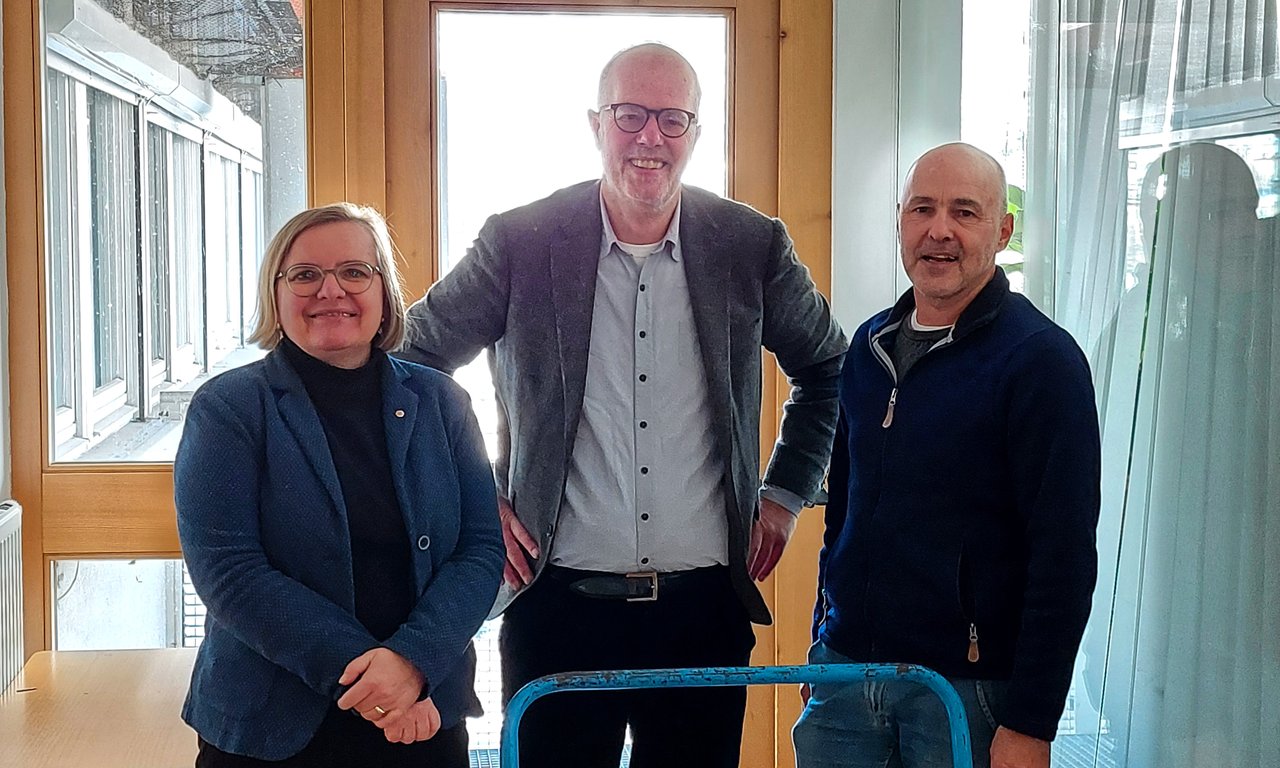 Drei Personen blicken in die Kamera