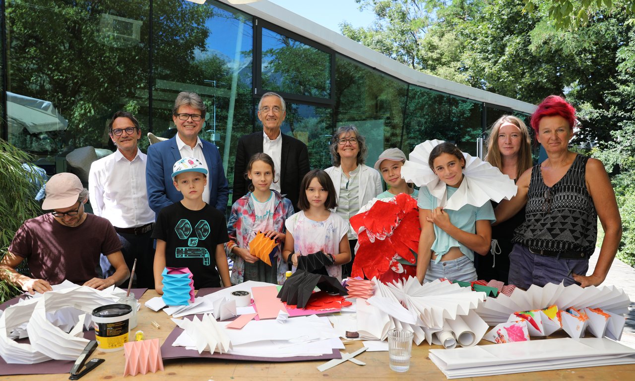 Zahlreiche Erwachsene und Kinder, im Vordergrund ein Tisch mit Bastelmaterial, im Hintergrund das Bilding in Innsbruck