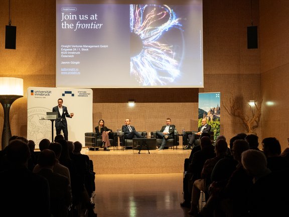 Foto von Vortragenden auf der Bühne und Publikum