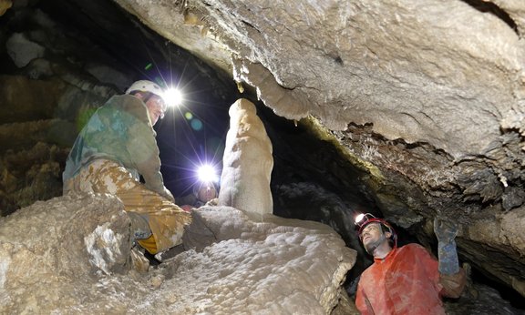Zwei Menschen mit Stirnlampen in einer Höhle
