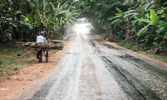 Mann schiebt Fahrrad neben einer Straße in Sansibar