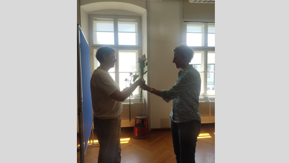 Zu sehen sind die Mitglieder des Instituts beim Sommerumtrunk. Es werden Blumen zum Geburtstag überreicht.