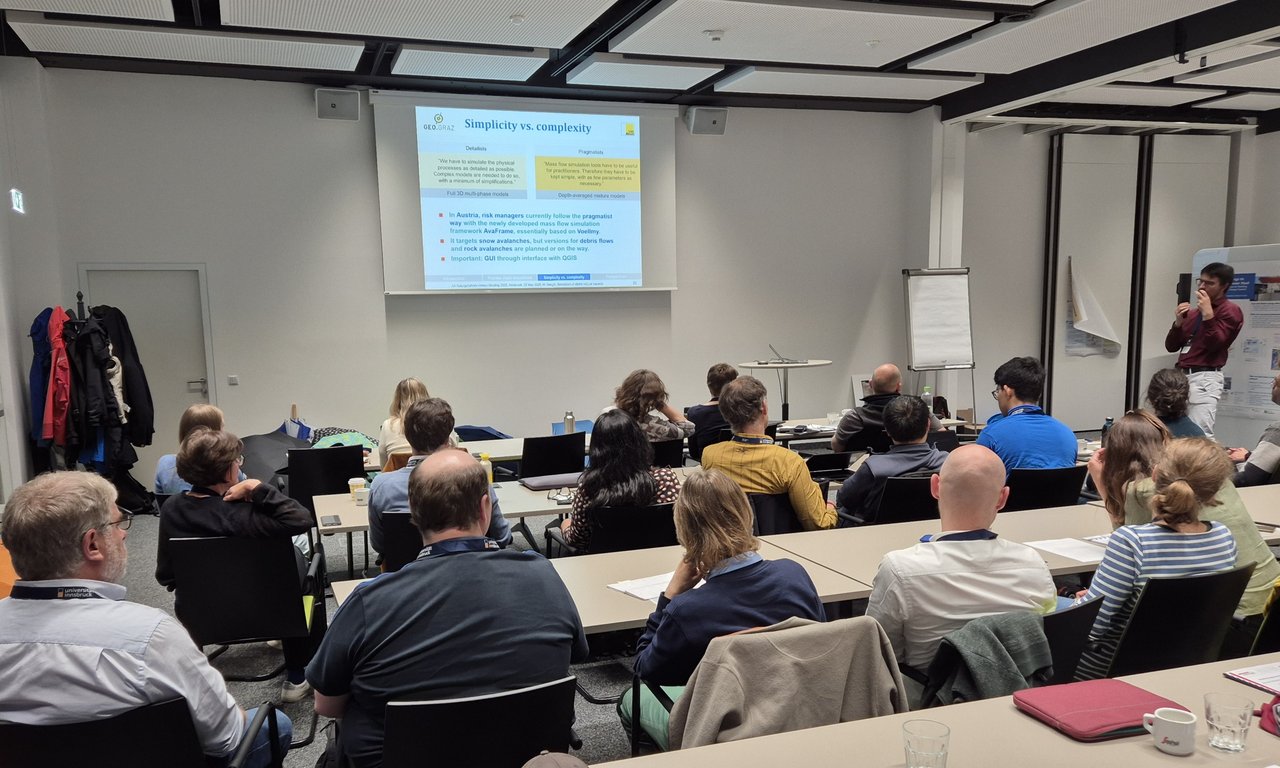 Seminarraum von hinten, etwa 10 Teilnehmer:innen, eine Powerpoint-Folie wird an die Wand projiziert.