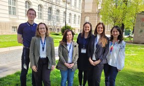 Zu sehen sind Teilnehmer:innen der Tagung. Sie stehen im Freien, auf einer Wiese vor dem Universitätsgebäude.