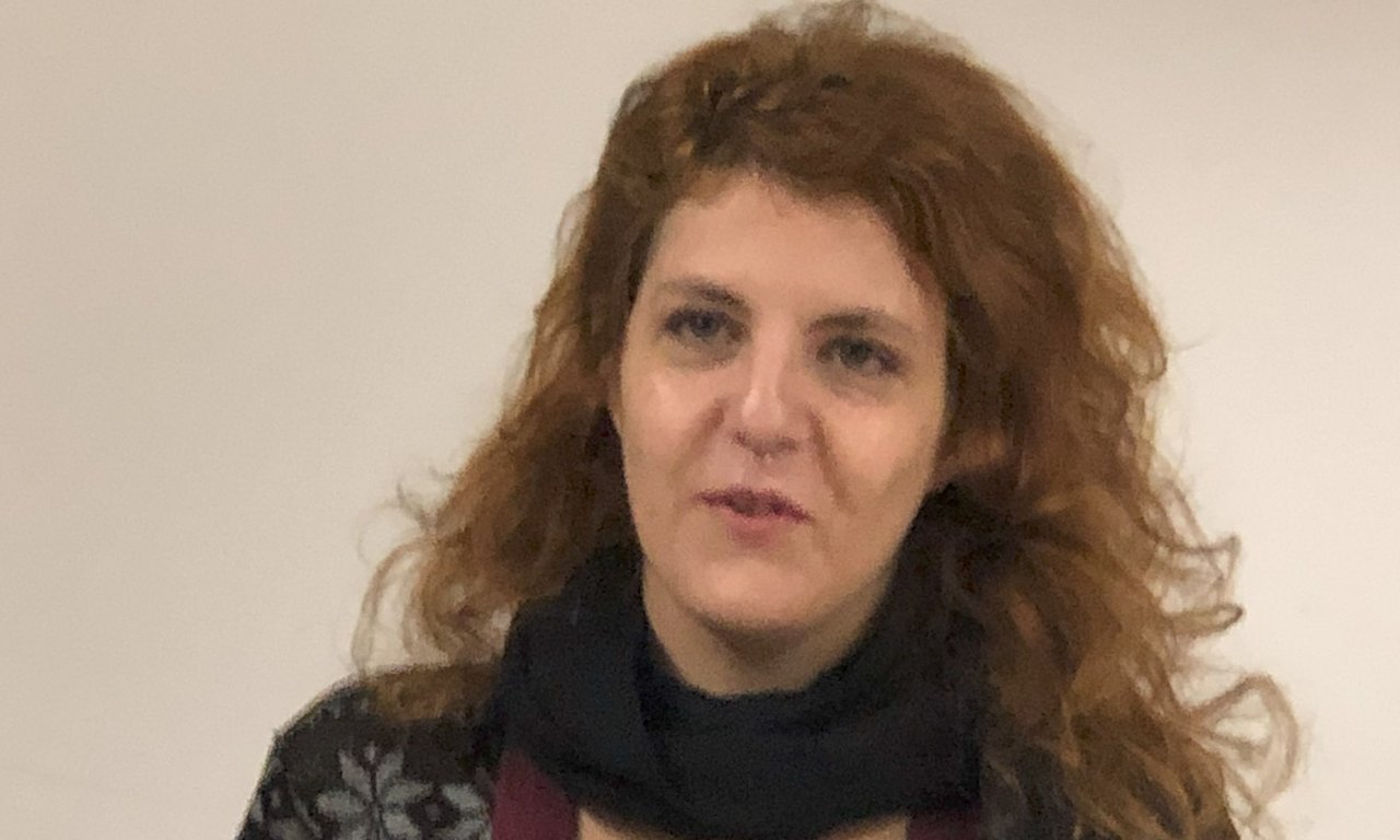 Eine Frau hält einen Vortrag, sie hat mehrere Blätter Papier in den Händen.