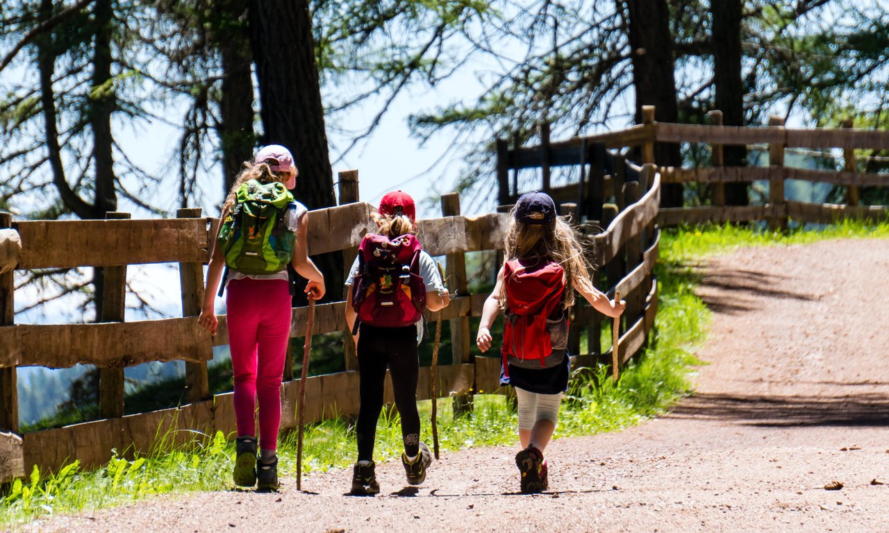 Drei Mädchen mit Rucksäcken auf einem Wanderweg