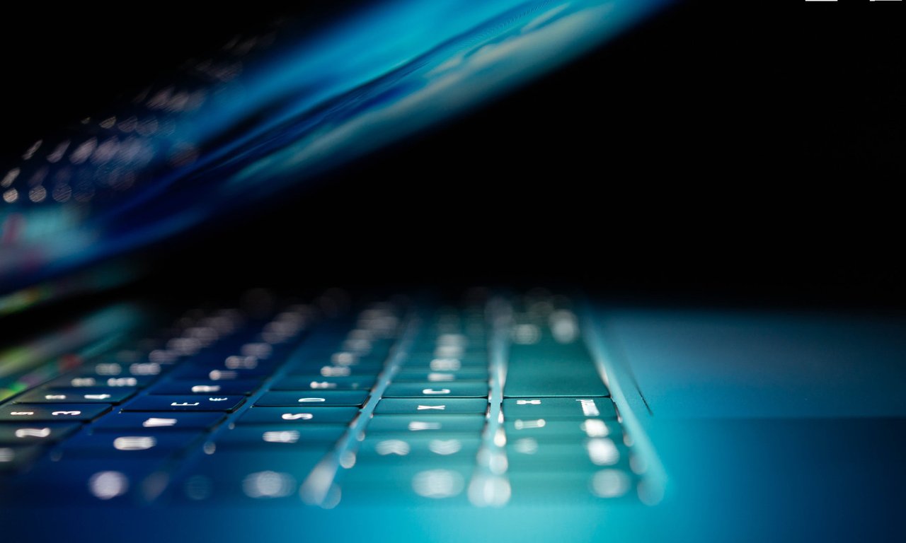 Aufgeklappter Laptop bei Dunkelheit mit beleuchteten asten.