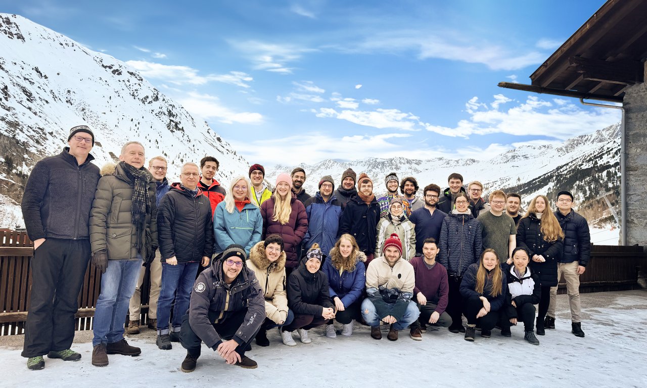 Zahlreiche Menschen in Winterkleidung vor schneebedeckten Bergen