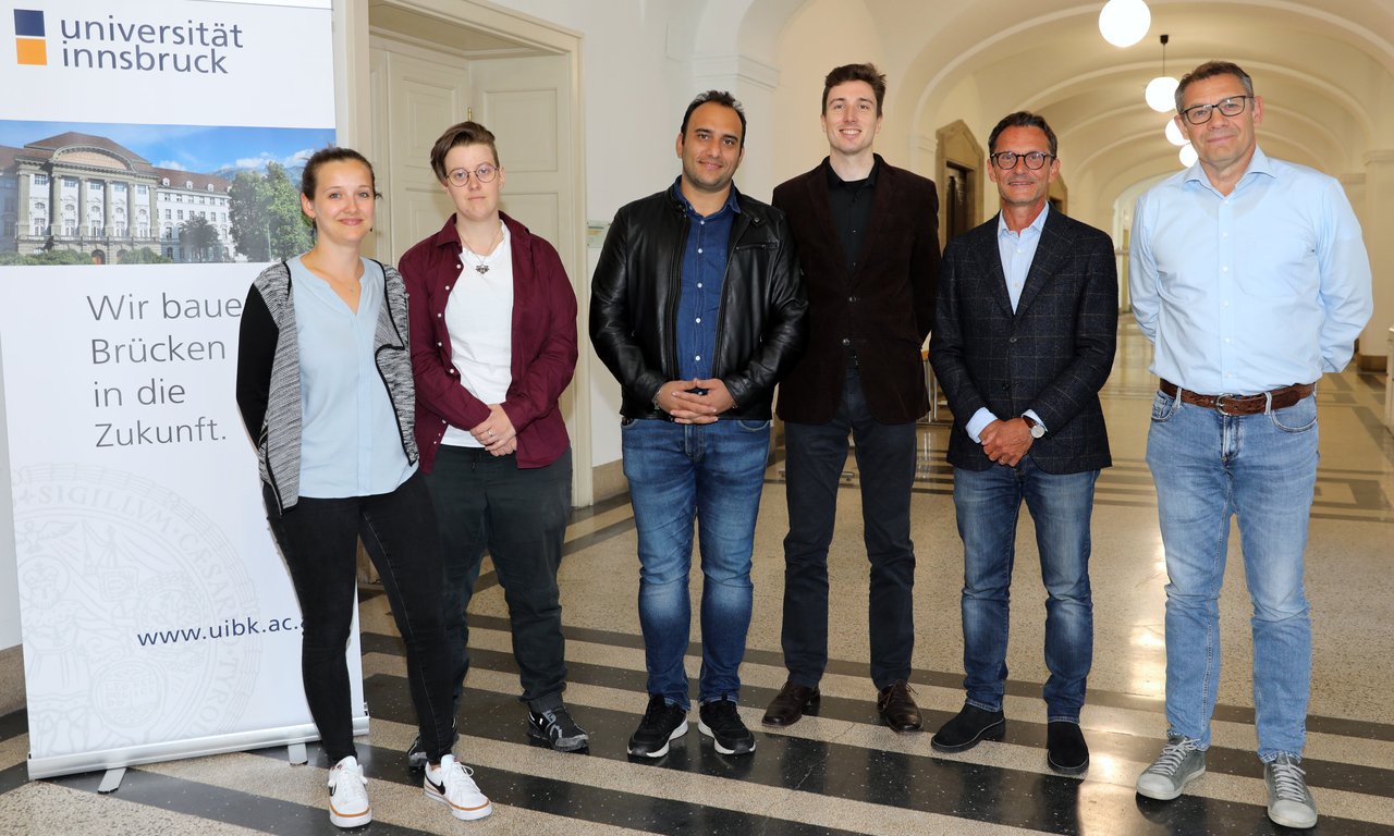 Sechs Personen stehen in einem Gang im Hauptgebäude der Universität