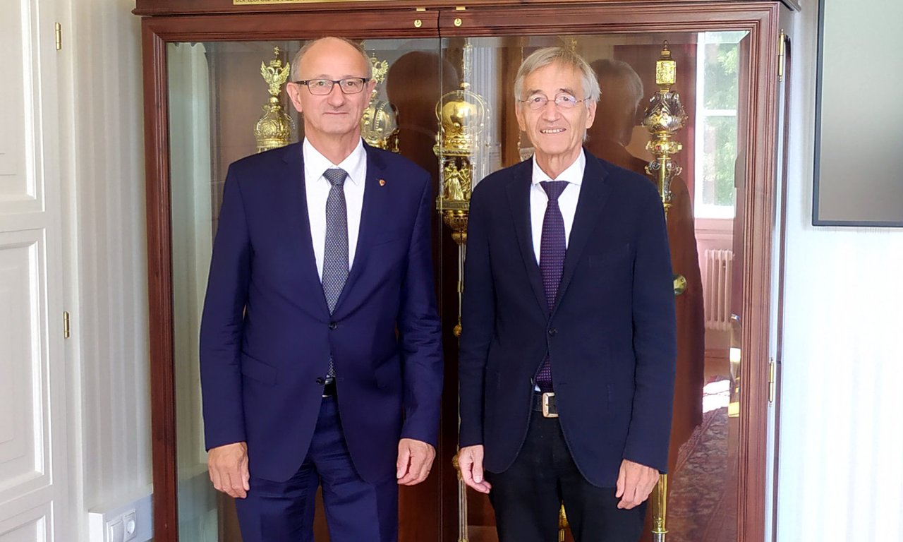 Anton Mattle und Tilmann Märk stehen im Salon des Rektor, im Hintergrund die Insignien der Universität