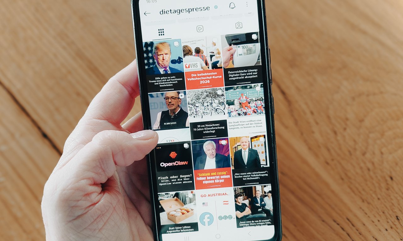 Nahaufnahme mit Blick auf Mobiltelefon, auf das Profil eine Online-Satireseite.